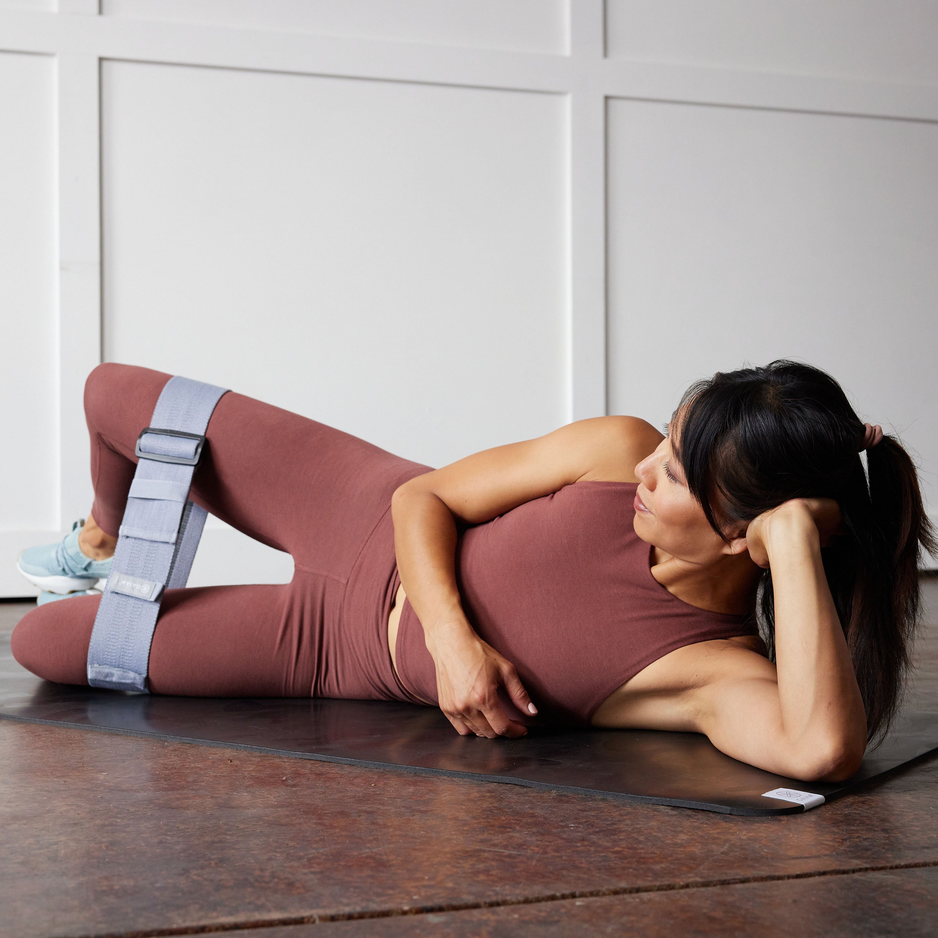 Person laying on side with hip band above the knee doing exercise